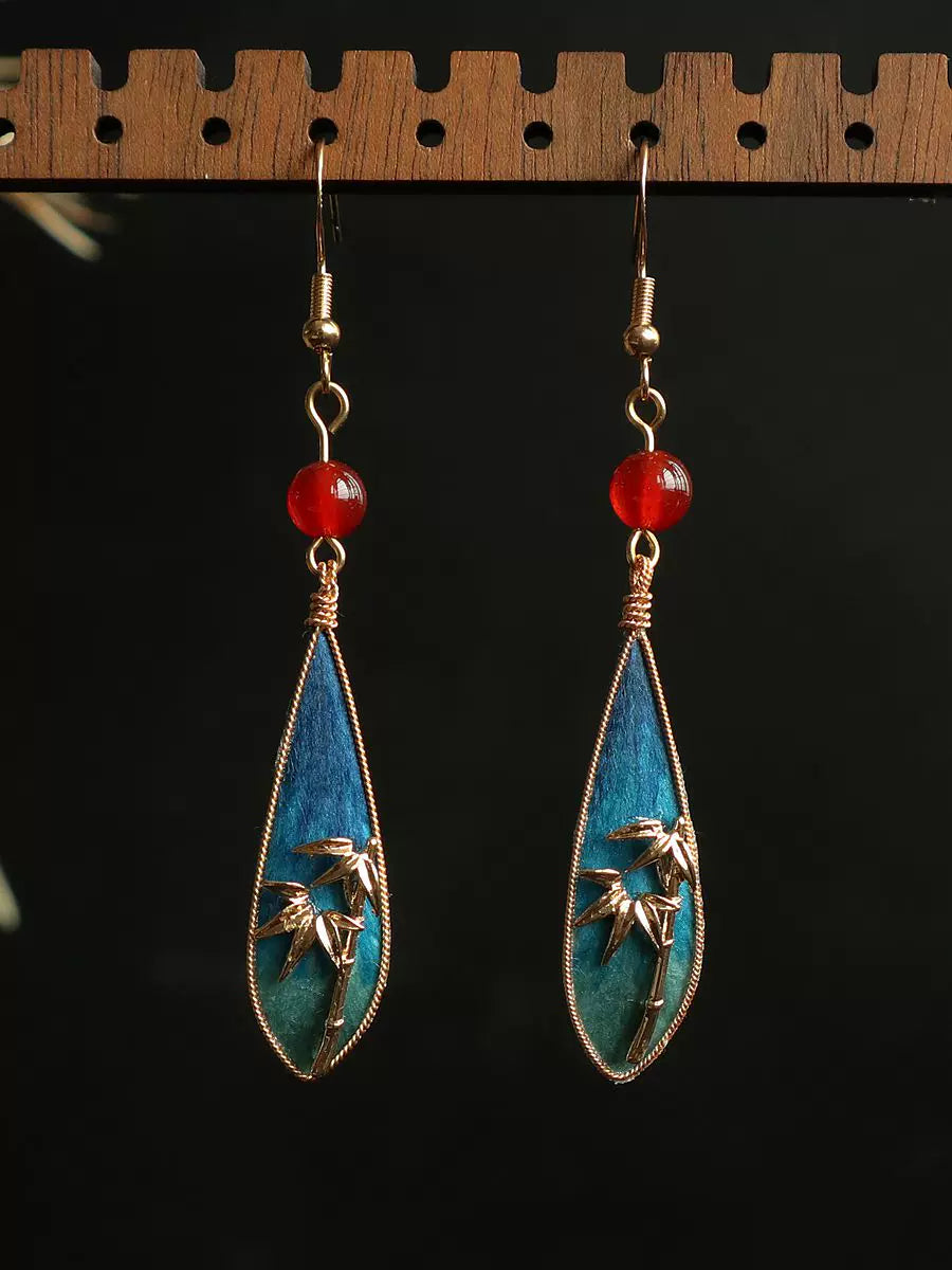 Hanging view of the bamboo leaf teardrop earrings with gold-tone wire details