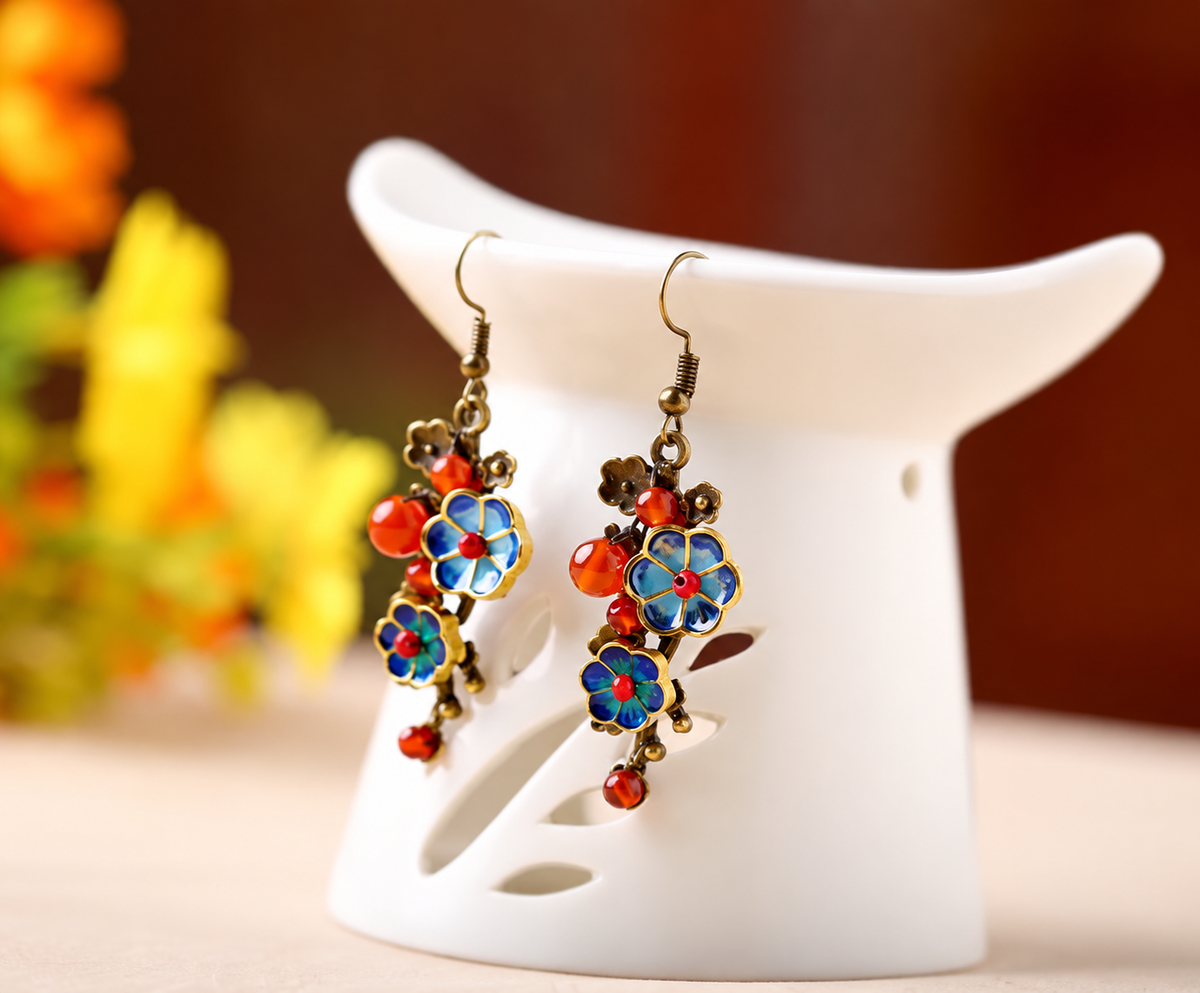 Blue cloisonne and red agate earrings on a white ceramic display stand