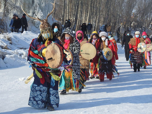 Ewenki cultural performers carrying frame drums during a winter procession