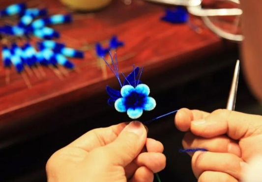 Artisan assembling a small blue Ronghua silk velvet flower by hand