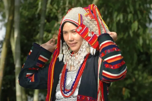 Woman adjusting a beaded headdress above a dark garment with colorful embroidered bands