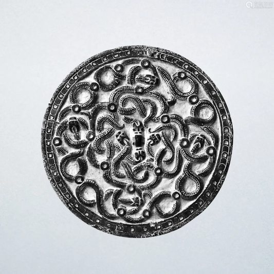 Reference image of a circular ornament with interlaced coiled animal motifs