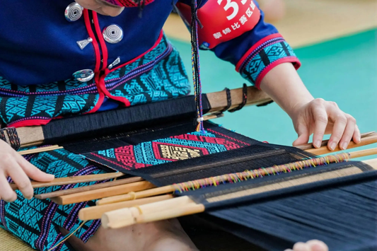 Close-up of a weaver forming colorful geometric patterns on a Li textile
