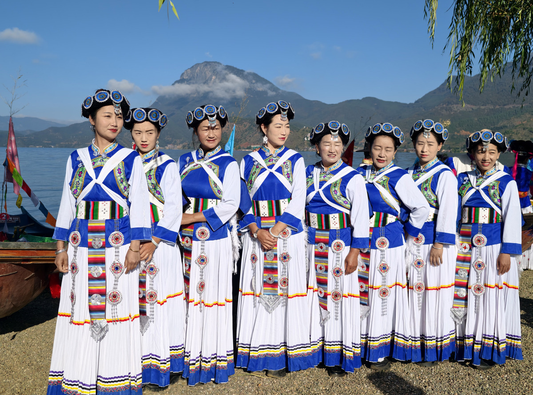 Naxi women in blue and white festival dress beside a mountain lake