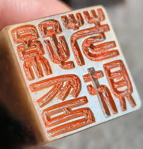 Close view of a hand-carved Chinese stone seal with red seal-script lines
