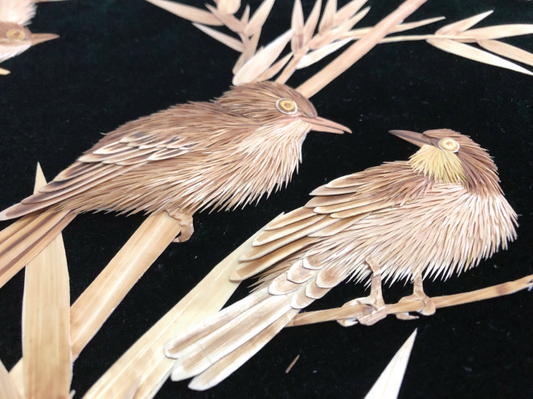 Two birds assembled from pale straw fibers on a dark background