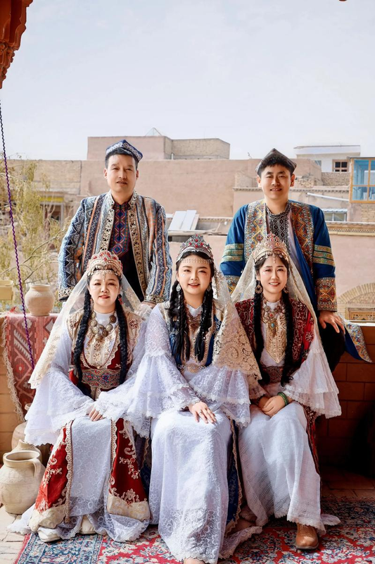 Group wearing ornate Uzbek-style ceremonial clothing in a Xinjiang courtyard