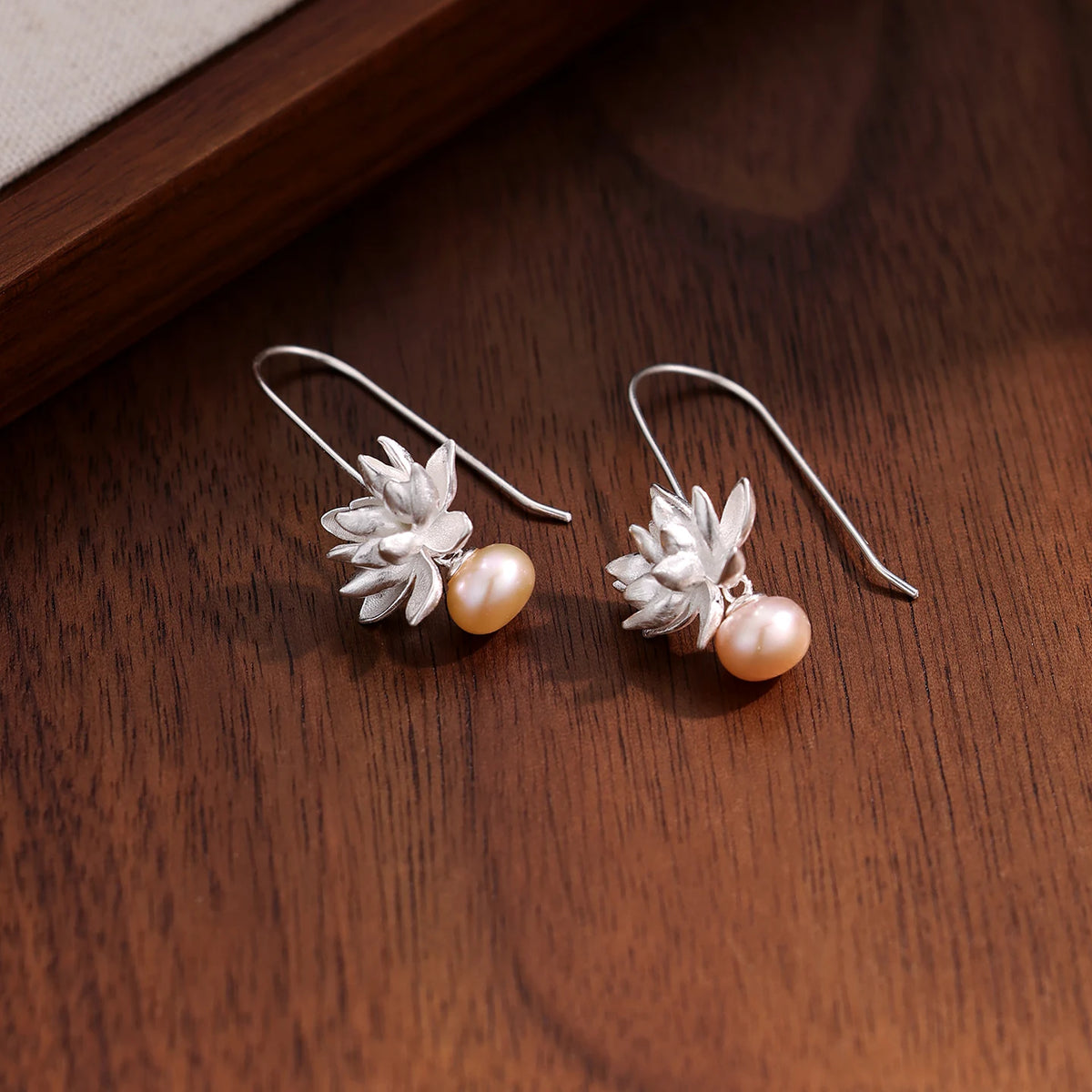 Sculpted lotus and pearl drop earrings, shown as a pair