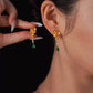 Gold-tone lotus-style drop earrings with green teardrop accents, shown worn