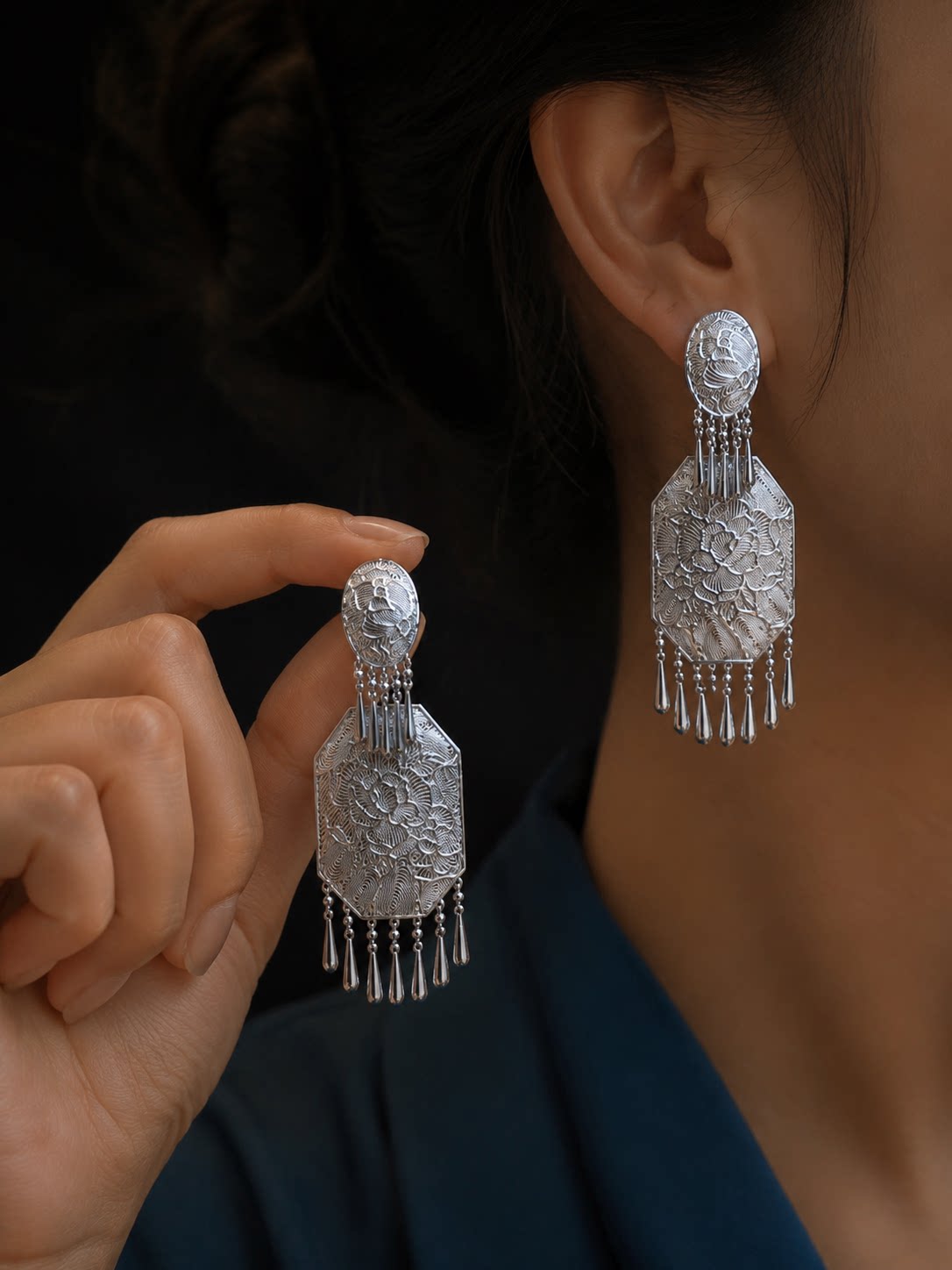 Pair of ornate peony tassel drop earrings shown worn and held in hand