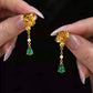 Close-up of the gold-tone lotus-style earrings with green drops