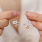 Lotus pearl drop earrings held for scale