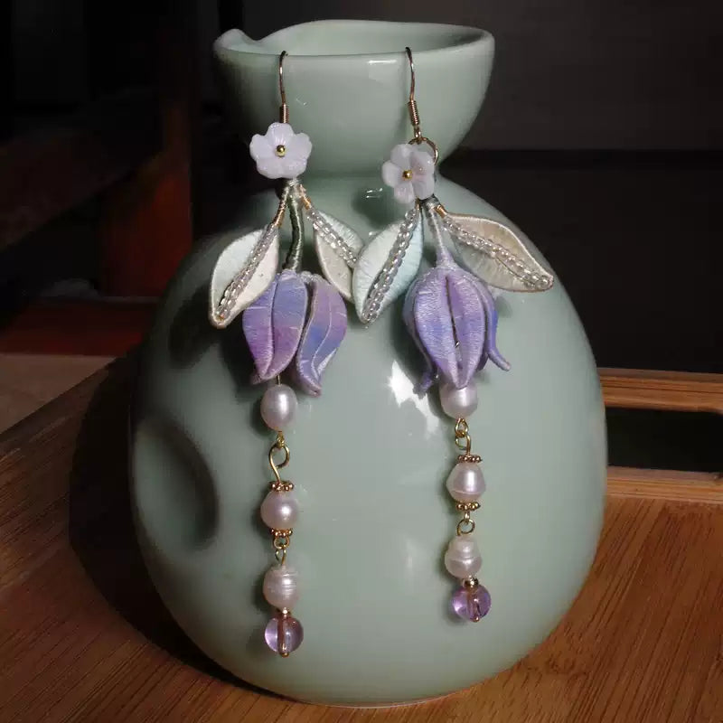 Lily of the valley earrings displayed on a ceramic stand, showing the long bead drops