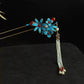 Blue floral double hairpin pair with hanging bead strands against a dark background