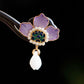 Close-up of purple peony petals, gold edging and drop ornament