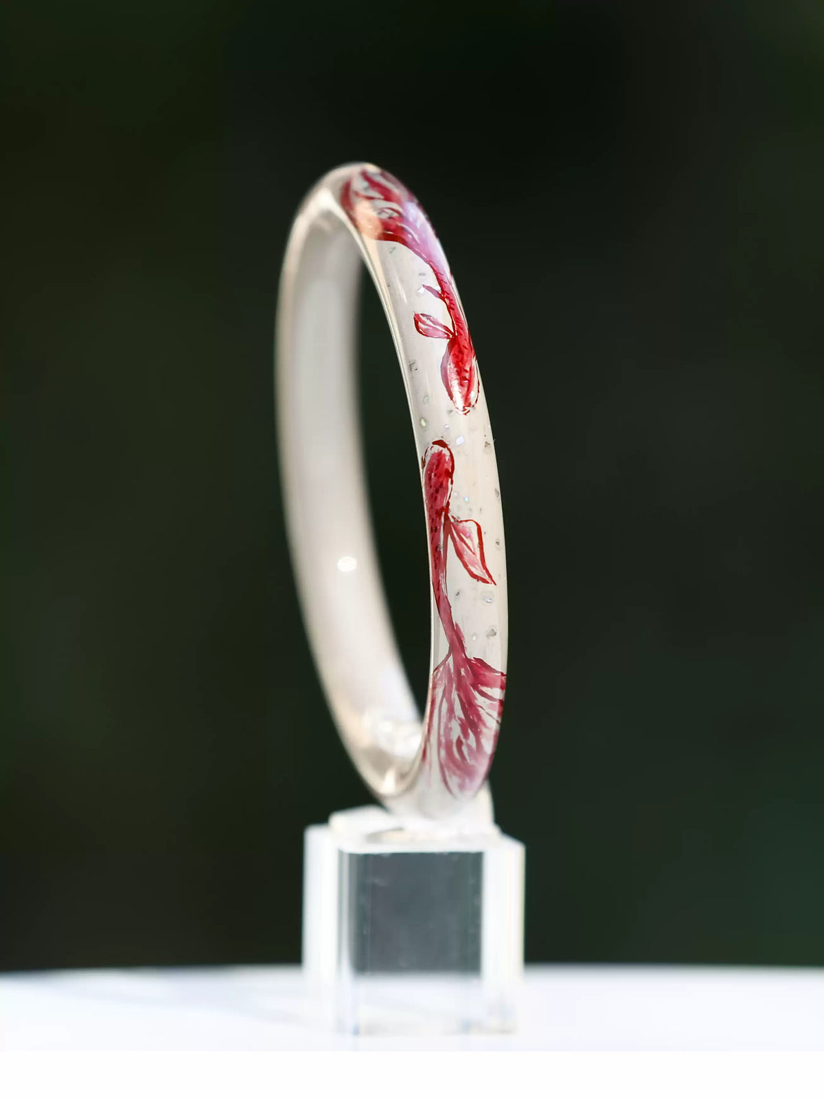 Three-quarter view of the koi motif bangle showing its circular shape and red fish decoration