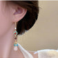 Long red and turquoise earring worn, detail view