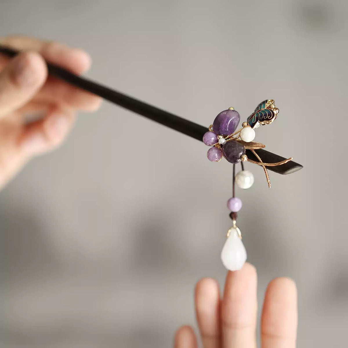 Close-up of purple stones, gold-tone branches, butterfly and dangling bead