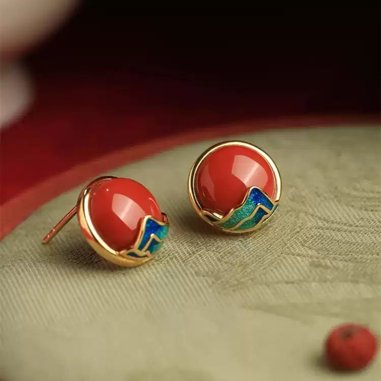 Front view of red round stud earrings with gold-tone and blue-green details.