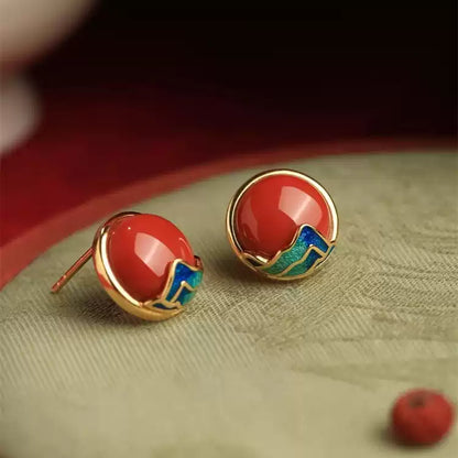 Front view of red round stud earrings with gold-tone and blue-green details.