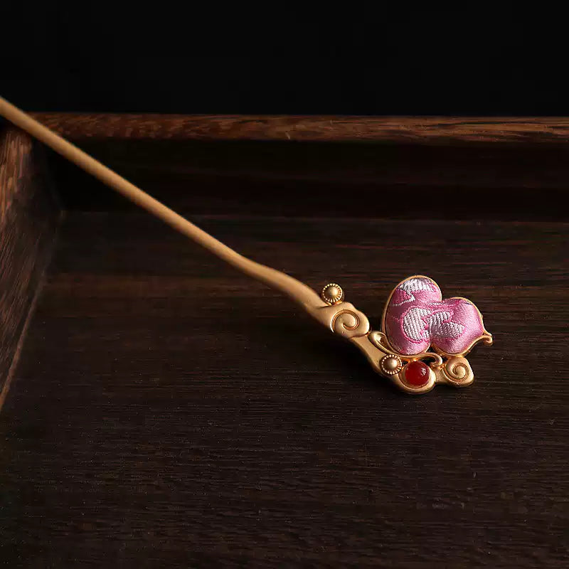 Pink fabric gourd hairpin with stitched floral detail and red accent bead