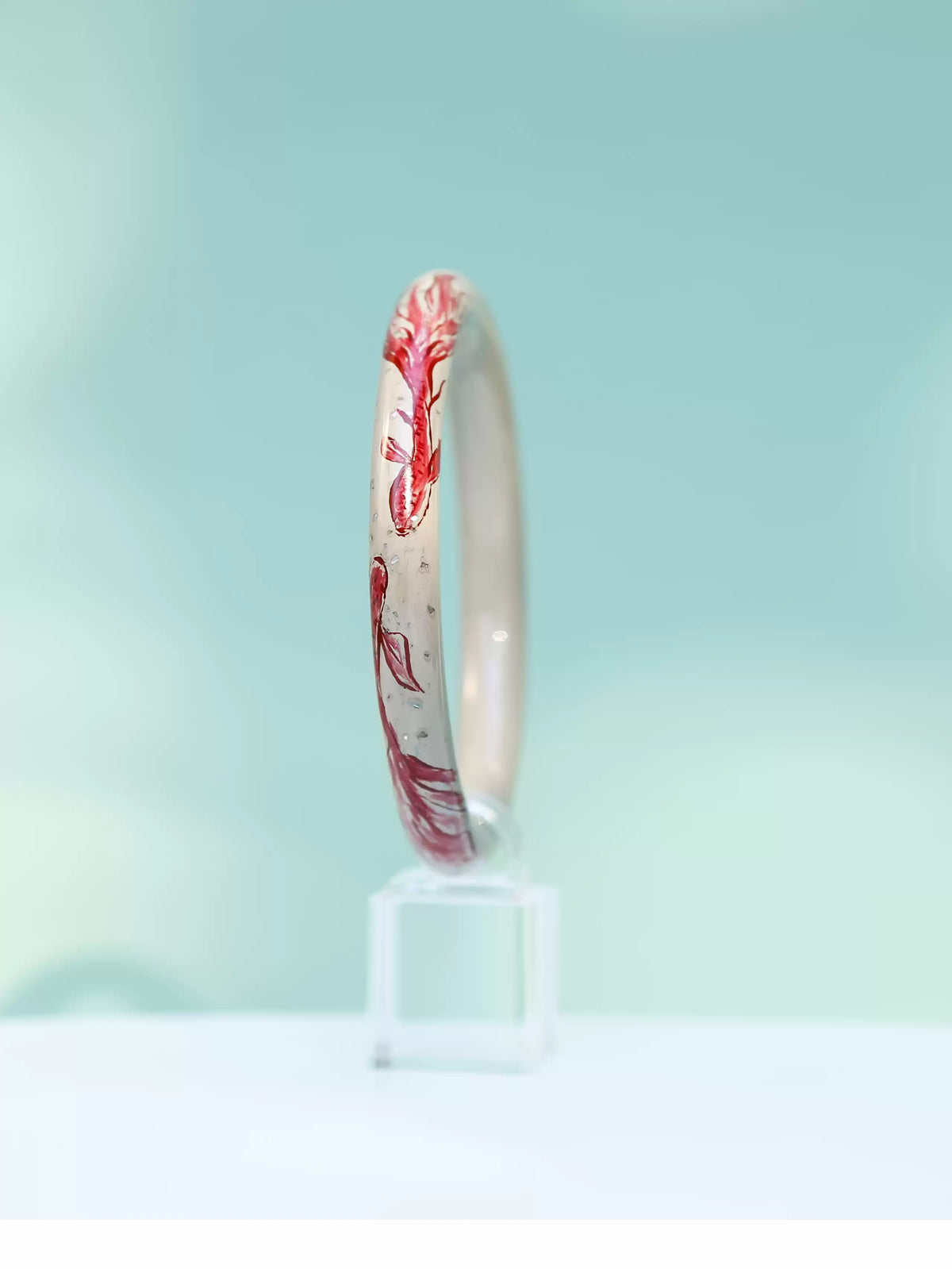 Side view of the koi motif bangle against a pale blue background