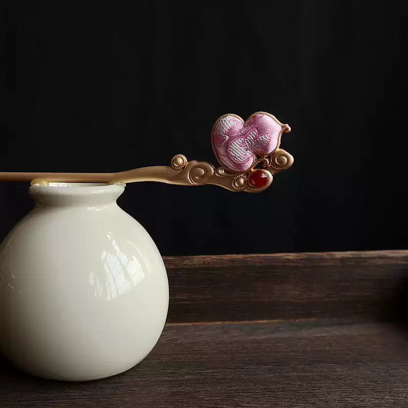 Pink fabric gourd hairpin displayed on a vase against a dark backdrop; vase is not included