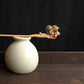 Pink fabric gourd hairpin displayed on a ceramic vase; vase is a styling prop