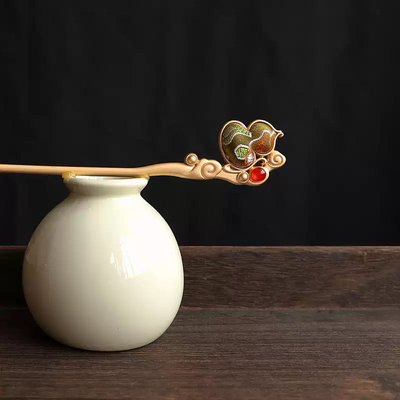 Pink fabric gourd hairpin displayed on a ceramic vase; vase is a styling prop