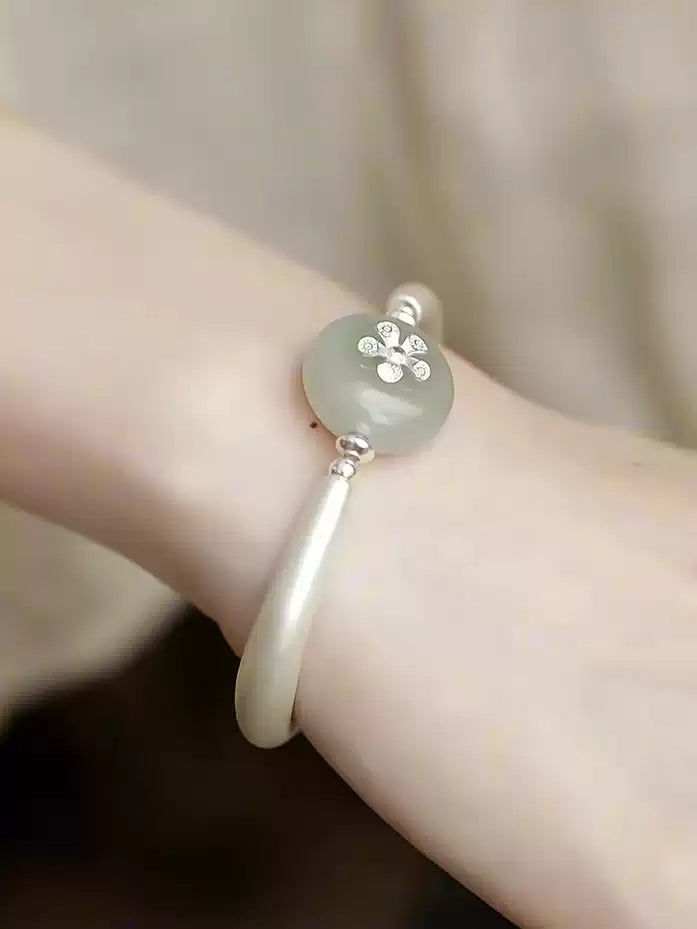 Silver-tone cuff bracelet with lotus pod charm styled on a wrist