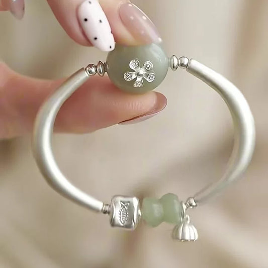 Silver-tone open cuff bracelet with pale green faux-jade-style beads and lotus pod charm, front view