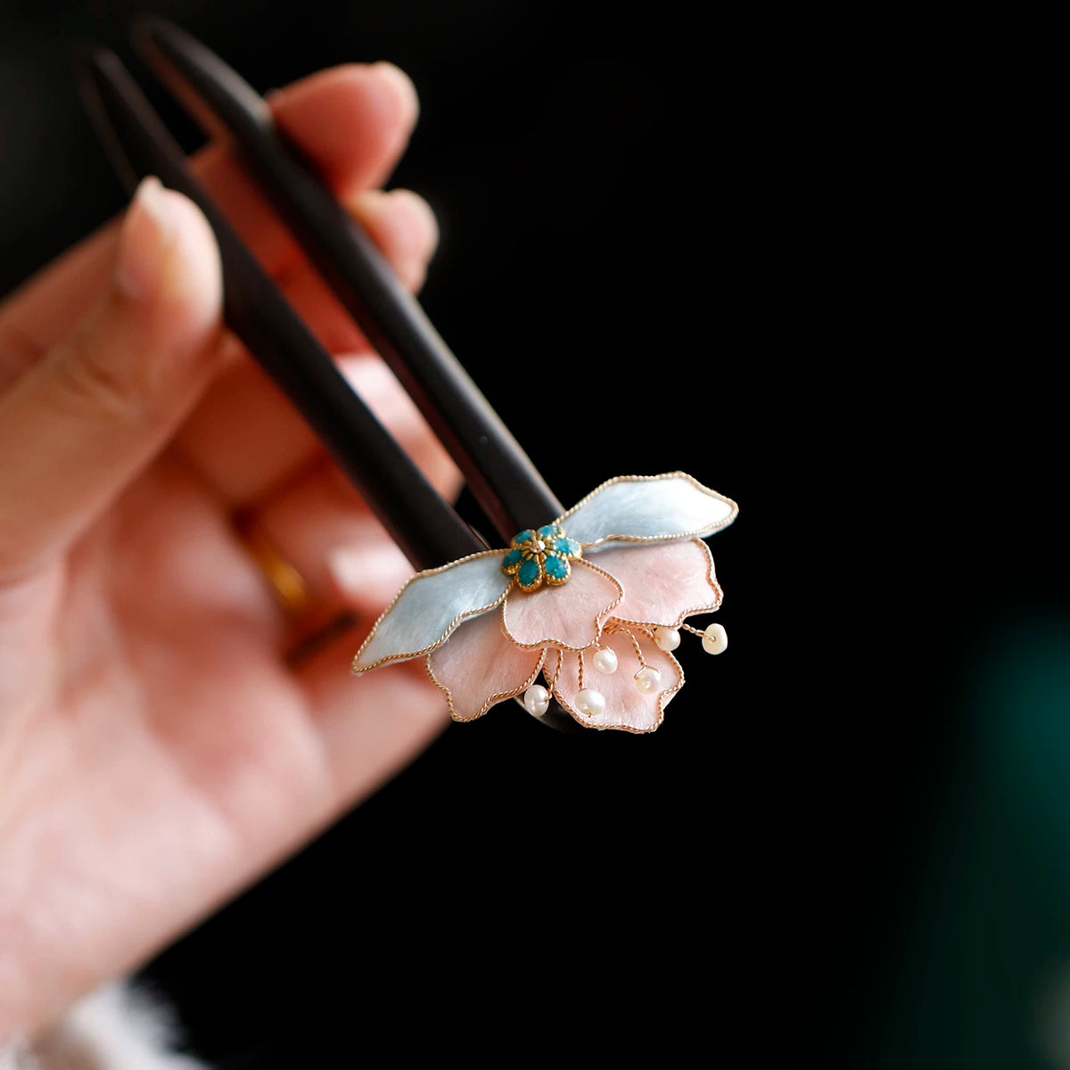 Pink and blue flower hairpin held in hand