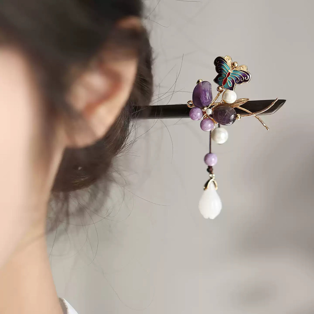 Side view of the purple butterfly hair stick with dangling beads