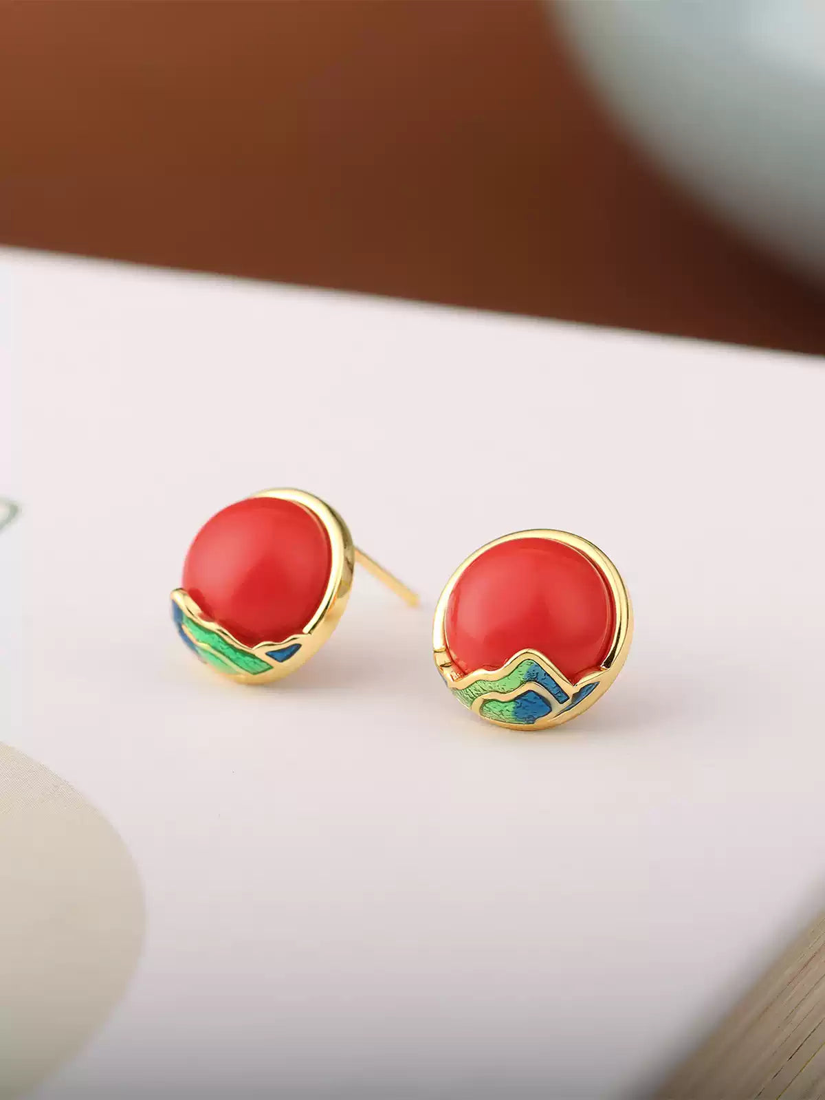 Red cabochon-style stud earrings with gold-tone and blue-green accents.