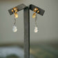Pair of long earrings with gold-tone flower details and pale imitation-jade-style gourd drops, arranged on a display stand.