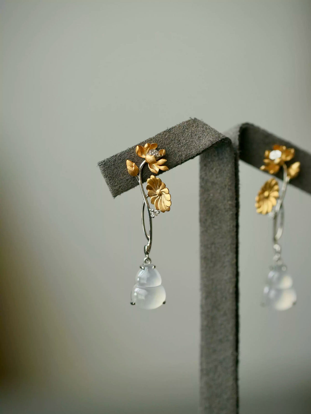 Long floral gourd drop earrings shown together on a neutral display stand.