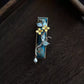 Front view of a deep blue brocade hair clip with flower and branch details