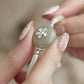 Close-up of pale green imitation jade-style bead and floral detail on the silver-tone bracelet