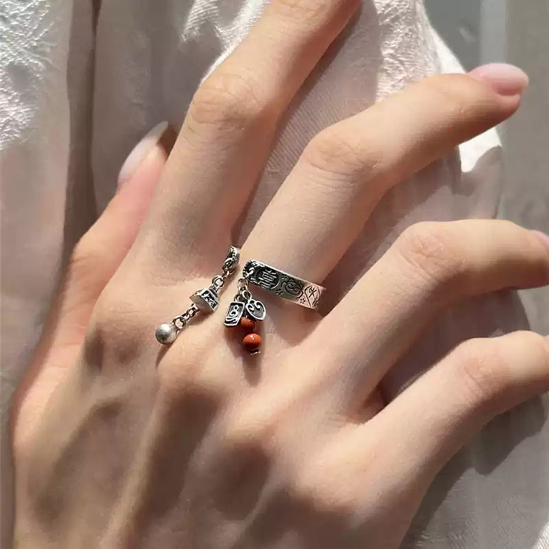 Silver-tone inscription ring with red bead charm, worn view