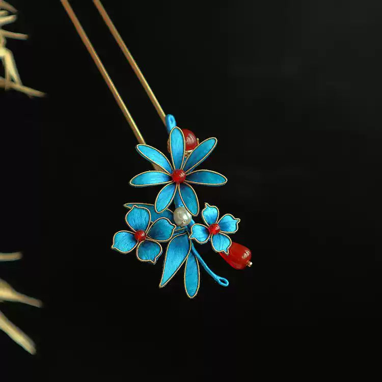 Flat lay of the blue floral double hairpin pair with gold-tone stems and dangling accents