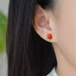 Close-up view of the red stud earrings being worn.