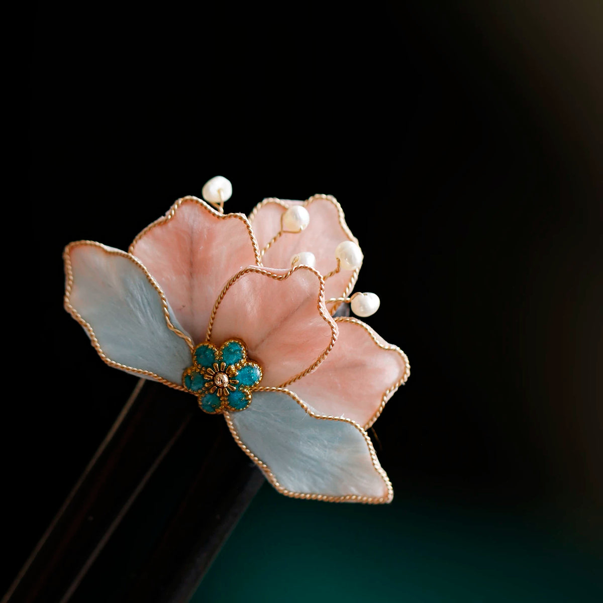 Pink and blue velvet flower detail on a wooden hairpin