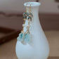 Pair of bamboo and quartz gourd drop earrings displayed on a white vase