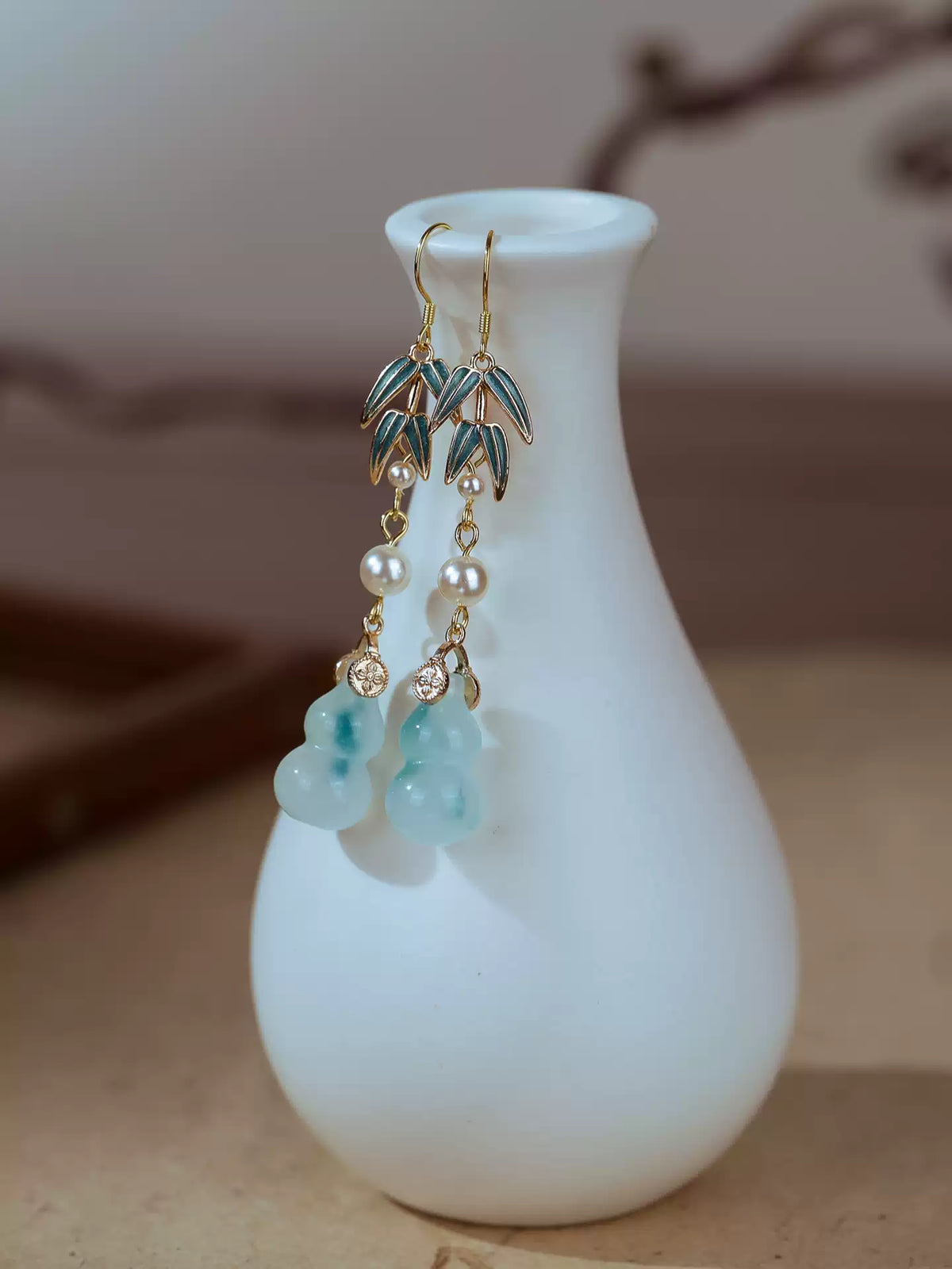 Pair of bamboo and quartz gourd drop earrings displayed on a white vase