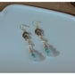 Bamboo leaf and gourd earrings with pierced-ear hooks resting on a white dish