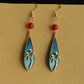 Front view of the blue-green bamboo motif earrings with red bead accents