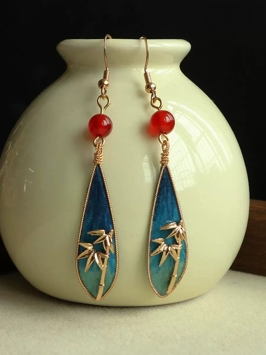 Pair of bamboo leaf teardrop earrings displayed against a dark background