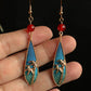 Hand-held scale view of the bamboo leaf earrings showing their drop shape
