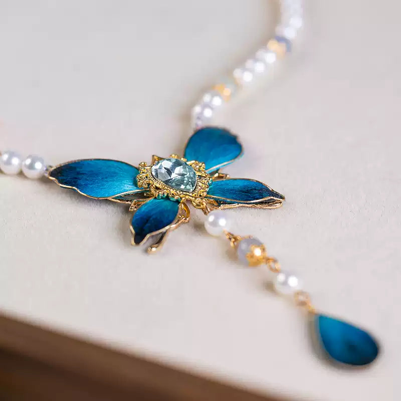Angled detail of the butterfly pendant, shell beads and blue accents