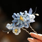 Blue chrysanthemum hairpin and decorative strands shown close up